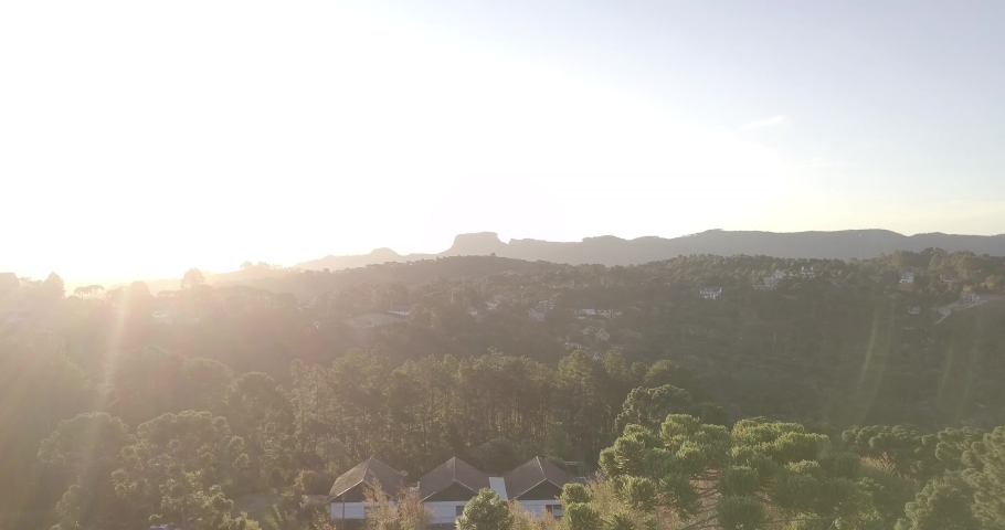 Beautiful aerial view of the city Campos do Jordao (jordan fields) in Brazil, with a mountain called Pedra do Bau (chest stone) and an amazing sunset at the horizon. Boom movement. Royalty-Free Stock Footage #1036210244