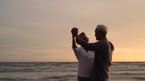 Asian couple senior elder retire resting relax dancing at sunset beach honeymoon family together happiness people lifestyle, Slow motion footage