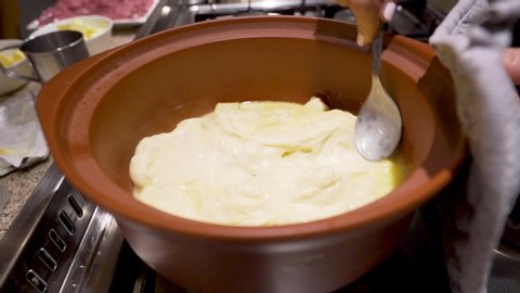 Close up Slow Motion shot a stirring melted cheese in a pot in preparation for fondue