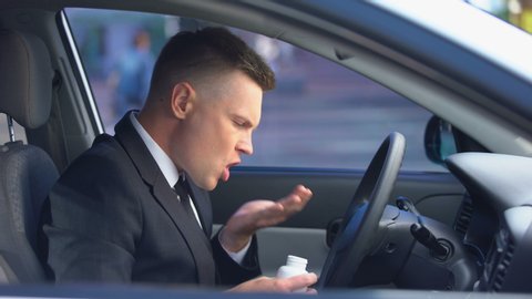 Nervous man in business suit taking drugs in car, opening window, feeling dizzy