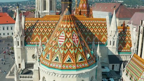 Budapest, Hungary - 4K drone flying away from the beautiful roof of Matthias Church in front of the Fisherman's Bastion at the heart of Buda's Castle District on a bright summer day