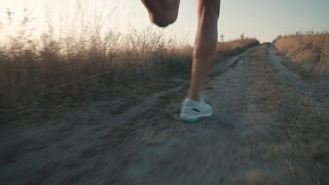 Runner Man Fit Athlete Legs Jogging On Trail Prepares To Triathlon.Triathlete Running,Sprinting And Workout Endurance Training.Running Man In Uphill At Sunset Slow Motion.Runner Marathon Jog On Trail.