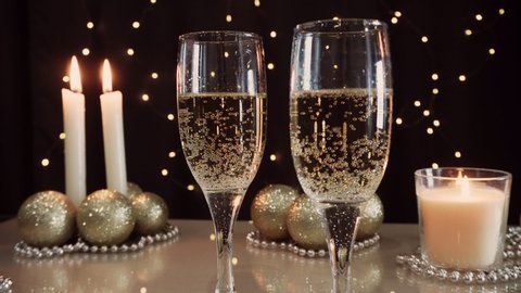 Christmas holiday. Golden glasses with sparkling champagne on the table. Christmas decorations and candles. Festive interior