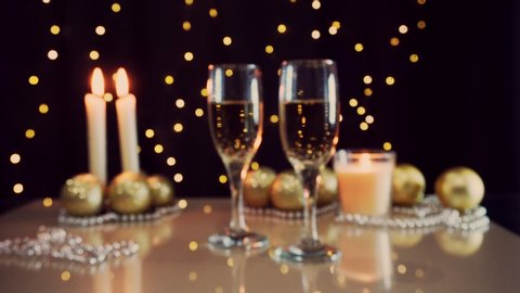 Christmas holiday. Golden glasses with sparkling champagne on the table. Christmas decorations and candles. Festive interior