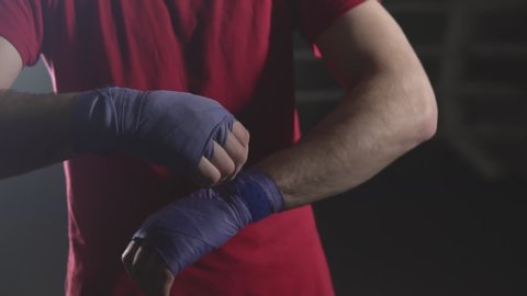 Close-up of kickboxer prepare for training. Man boxer wapping hands getting ready for fight in slow motion