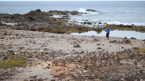 Woman runs along the stony shore of the ocean. Healthy active lifestyle. Slow motion