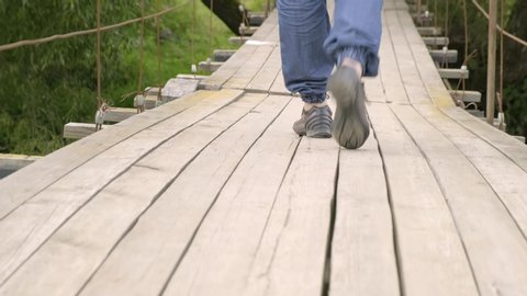 Legs of man walking on suspension bridge close-up. suspension bridge staggers when a person is walking along it.