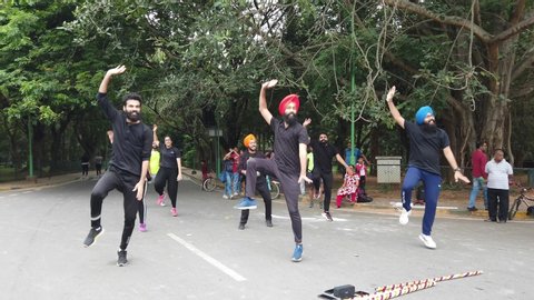 Bengaluru, Karnataka / India - September 1 2019: Slow motion shot of a Punjabi flash mob perfroming bhangra dancing to a song in Cubbon park on a bright day