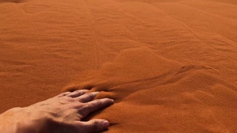 Slow motion shot of a man's handing through sand in the Wadi Rum Desert, Jordan.