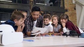 Shooting of group of six curious school children of different ethnicities smiling while watching their Korean male teacher use device of tablet computer for to run electronic designer at school. Slow - Powered by Shutterstock - Get 15% off with code: PIKWIZARD15