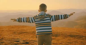 Children running outside. Happy traveler boy playing on sunny day in park. 4K slow motion video. Child runs on top of mountain at sunset. Journey to the Edge of the Universe
