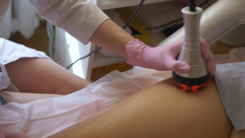 Rf skin tightening, belly. The hand of a beautician making procedure on the patient's leg.