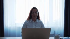 Young attractive caucasian woman smiling and making video call or online chat, looks at web camera of laptop. Distant teacher or coach, or tutor of online school or internet friend concept