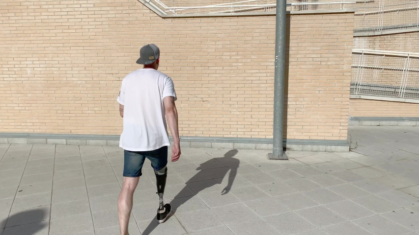 Young man with orthopedic leg prosthesis jumping between buildings practicing parkour | Shutterstock HD Video #1036256345