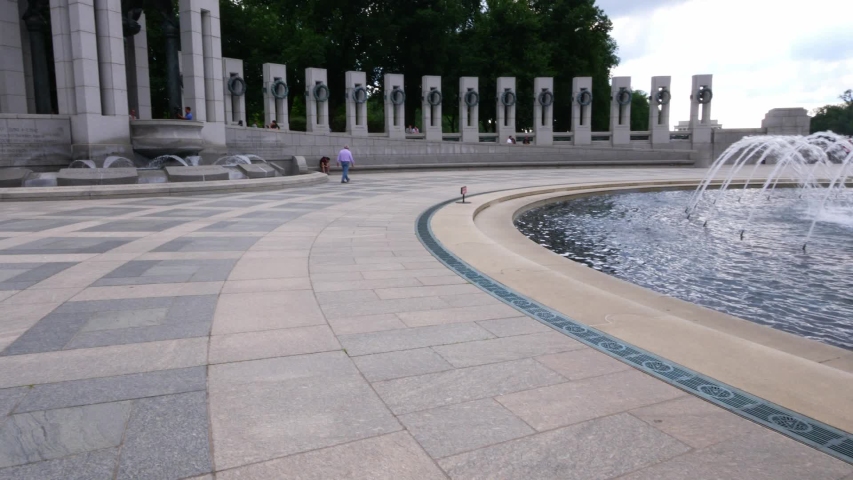 A beautiful respectful view of the World War II memorial, its fountains, and the pacific pillar located at the National Mall.