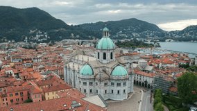 Roman Catholic Cathedral in Como city - Italy near Milan. Drone aerial footage flying around the Cathedral building as a point of interest. Como Lake and Mountains on the background.