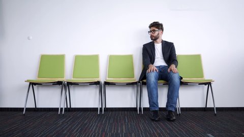 Impatient and stressed young man waiting for job interview in hallway