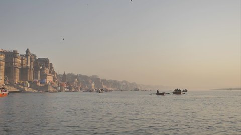 A wide shot of the Varanasi ghat and the river Ganges during sunrise