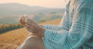 Close-up of female hands, Woman tourist traveler relaxing on field, top of mountain in summer sunny day under sun light. Beautiful mountains landscape view. 4K slow motion video
