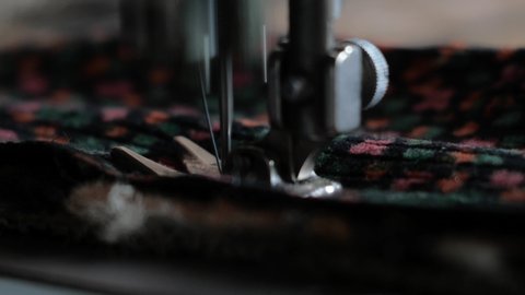 Sewing Machine Needle in Motion. Close-up of sewing machine needle rapidly moves up and down. The tailor sews fabric on the sewing workshop. The process of sewing fabric.