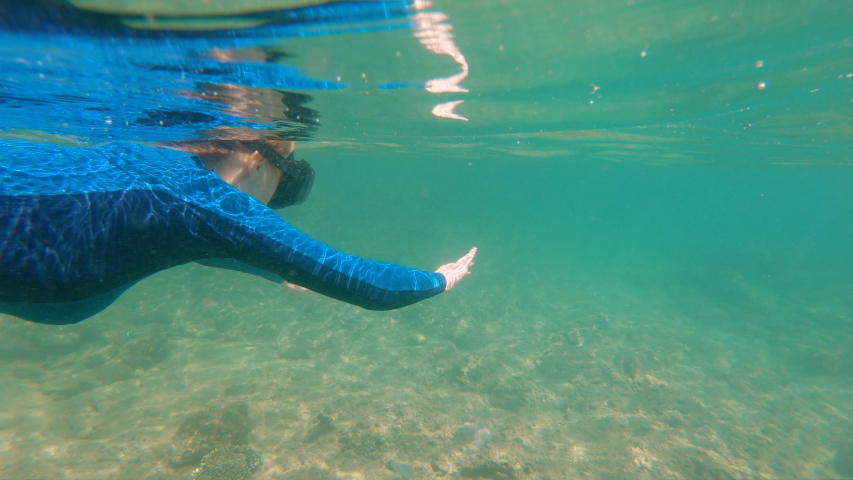 Slowmotion shot of a young woman snorkeling and diving in a beautiful sea