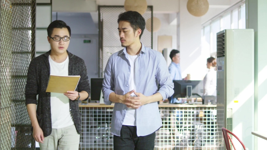 two young asian businessmen discussing business while walking in office of small company Royalty-Free Stock Footage #1036279076