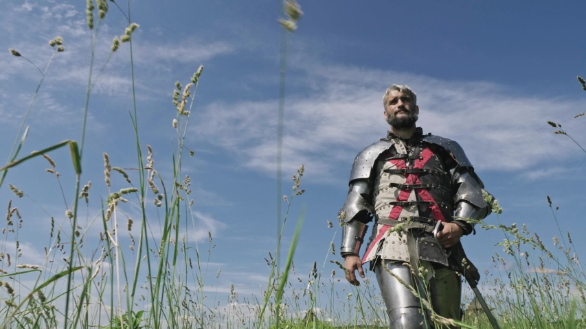 Medieval knight going against blue sky. Knight wearing traditional steel armor.