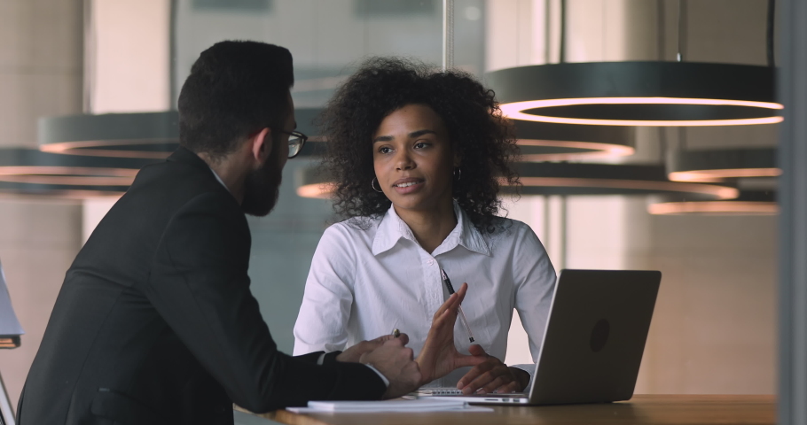 Female african manager broker advisor consulting arabic male client with laptop talking discussing bank loan deal benefits with arab customer collaborating convincing buy insurance services in office Royalty-Free Stock Footage #1036284905