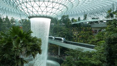 Changi, Singapore - Circa September 2019 Waterfall inside glass dome at Jewel at Changi with train passing across