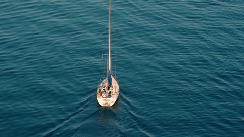 small sailboat sails over the sea from the bird's perspective, viewed from above