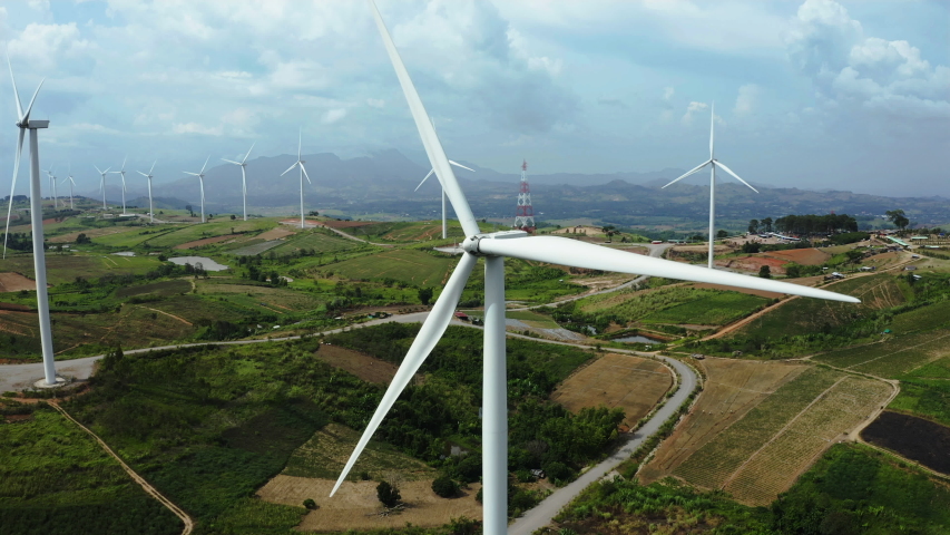 Aerial view, windmills rotating by the force of the wind and generating clean renewable energy for sustainable development in a green ecologic way on cloudy sky at highland. The look up shot by drone | Shutterstock HD Video #1036297355
