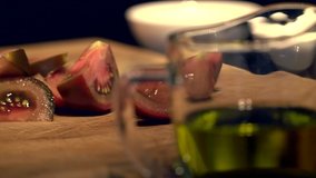 Hands of an Italian cook preparing dinner on a wooden board. Close-up video. Cut red Sicilian tomatoes with a sharp knife for a cold fish dish. Mediterranean Kitchen