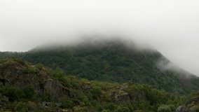 4K footage of the beautiful rain clouds and fog movement on the top of the mountain after stops raining. The rain clouds and fog are melting, Norway