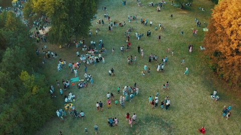 Crowd of people are walking, playing and having a picnic outdoors at summer. People having their carefree time in public park. Aerial view from above 4k