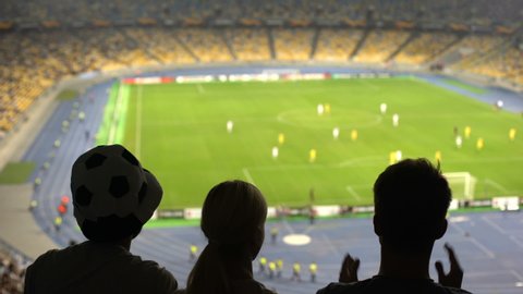 Group of fans cheering for football team victory at crowded stadium, competition