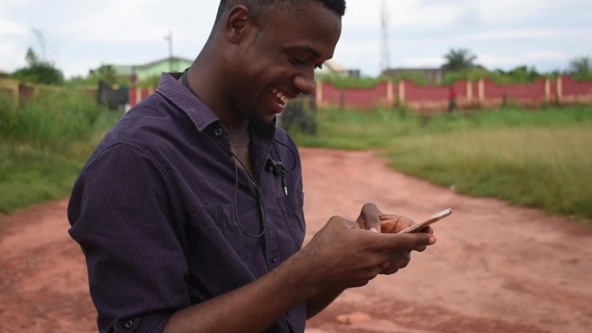 a young African american man chatting with his mobile phone outside the street  and feels excited with what he is seeing on his phone Royalty-Free Stock Footage #1036314272