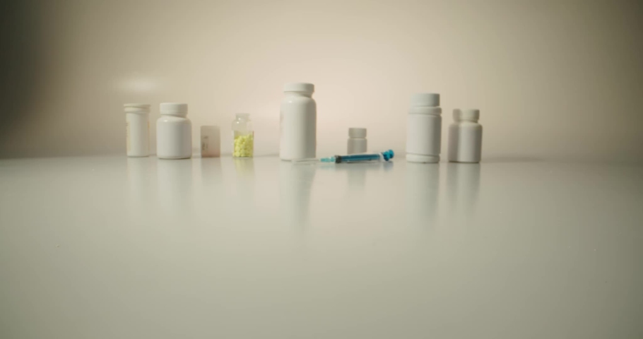 Closeup shot of different pills falling on table with tablets cans and syringes - mosern drug and pharmacy addiction, pharmaceutical industry concept 4k footage Royalty-Free Stock Footage #1036322543