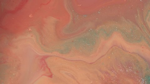 Close up of peach glitter texture background. Pastel coral, blue and pink colors liquid paint. Abstract fluid makeup composition. Hypnotic mixing and movement of the ink