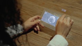 Unrecognizable woman working on a futuristic tablet with a hologram planet Earth. Women's hands with future holographic technology at a wooden table - Powered by Shutterstock - Get 15% off with code: PIKWIZARD15