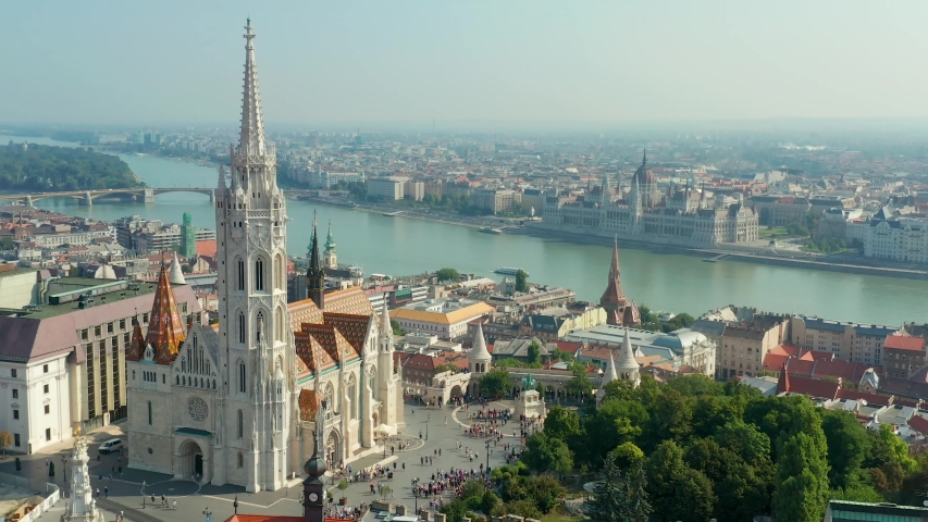 Budapest, Hungary - 4K drone flying at Fisherman's Bastion by Matthias Church with clocktower and Parliament of Hungary at background on a sunny summer day