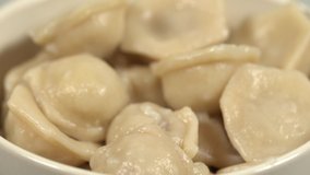 Closeup view of hot fresh just cooked tasty pelmeni stuffed with meat laying in bowl. Food rotating around. Real time 4k video footage. 