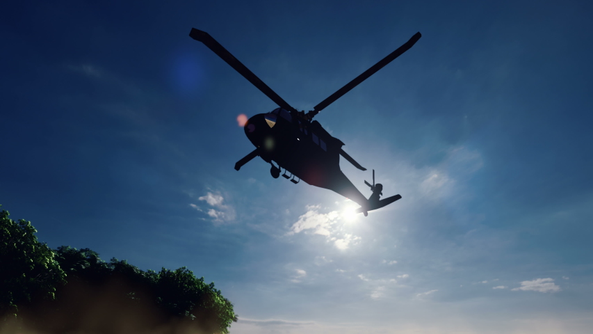 A Blackhawk military helicopter lands on a dusty road on a clear day in a deserted area.