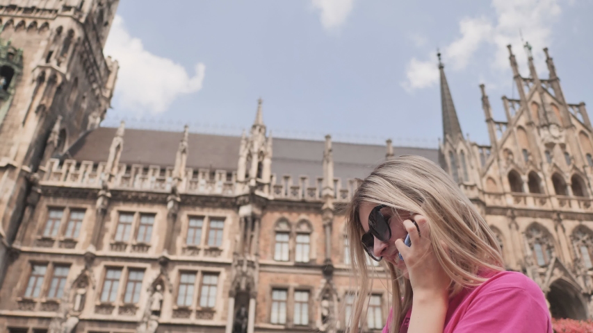 Girl talking on the phone against the background of the city hall in Munich. Germany.