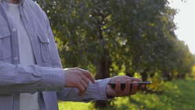 Unrecognizable man shows conceptual hologram with particles. Farmer on the background of the apple orchard in casual clothes with the technology of the future mobile screen - Powered by Shutterstock - Get 15% off with code: PIKWIZARD15
