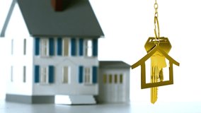 Animation of golden house keys and house shaped key fob hanging over a 3d house model and a word Home in wooden blocks on a white background - Powered by Shutterstock - Get 15% off with code: PIKWIZARD15