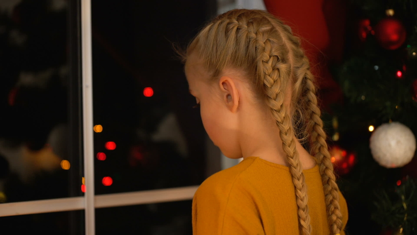 Little abandoned girl putting candy in one sock, preparing present, Xmas eve