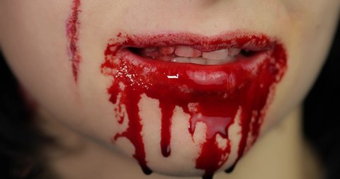 Bloody mouth and teeth of girl. Vampire woman Halloween makeup with dripping blood. Friday 13th theme