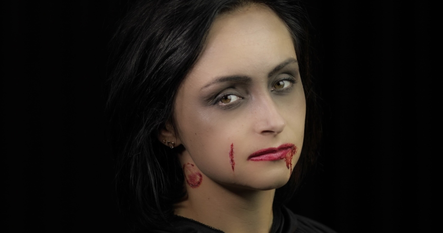 Vampire Halloween woman portrait. Beauty sexy Vampire girl with dripping blood on her mouth. Vampire makeup. Fashion Art design. Attractive model girl in Halloween costume