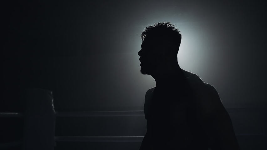 Angry man with boxing gloves emotionally standing on the boxing ring. Slow, motion, silhouette. Boxing concept. Royalty-Free Stock Footage #1036358375
