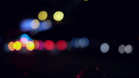 Beautiful glittering bokeh in dark blurry background at night. The round colorful bokeh shine from car lights in traffic jam on city street. It reflect lonely capital city lifestyle. Abstract concept.